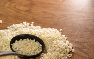 Corn for preparing hominy dish in shell on woody background