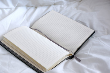 green notebook, in a white bed. Coziness. Minimalism.