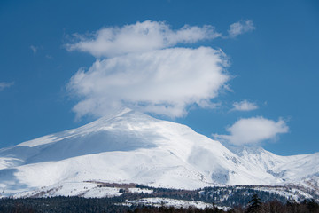 春先の雲と雪山