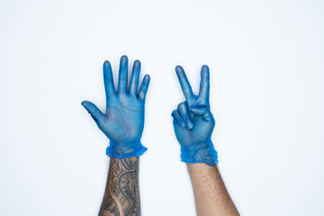 A man hand and gestures in Blue rubber glove shows seven finger sign isolated on white background.