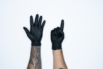 A man hand and gestures in Black rubber glove shows six sign isolated on white background.