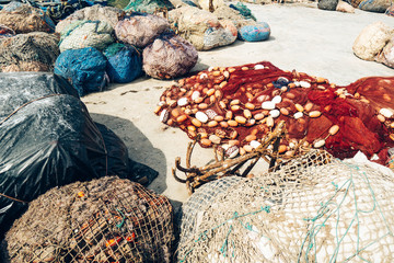 Multi-colored fishing nets and anchor on the shore in the port.