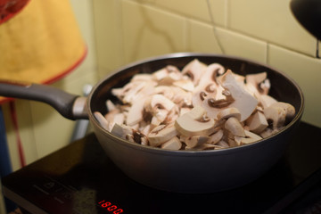 Frying pan with mushrooms on the stove in the kitchen