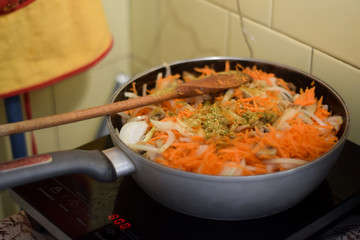 Frying pan with vegetables on the stove in the kitchen