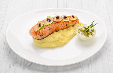 Grilled salmon, boiled potatoes and vegetables on a white plate
