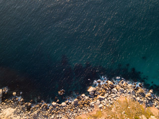 Aerial of rocky coastline and deep clear sea from above