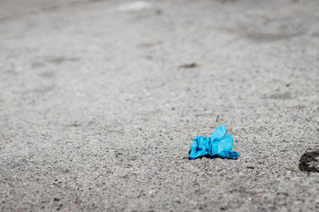 A used blue glove is placed on the floor in the street, used to protect against the corona virus