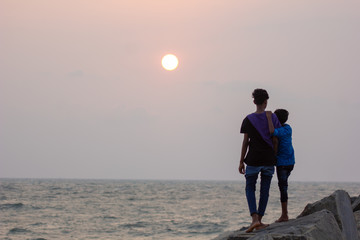 Silhouette of brothers on the beach at sunset