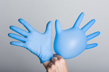 Obraz premium Hand putting on blue glove, on grey background