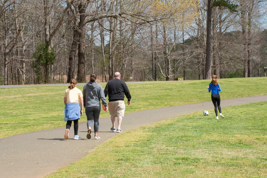 A family walking along a park trail - Powered by Adobe