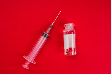 medical ampoules and syringe on red background