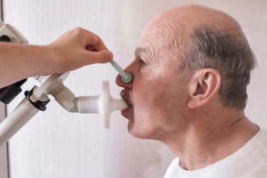 Senior hispanic man man testing breathing function by spirometry.