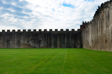 Fototapeta na wymiar Brick wall on green lawn, squer - Pisa, Italy