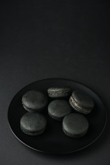 top view of plate with dark and tasty macarons on black