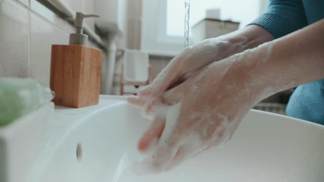 Young woman washing hands with antibacterial soap in the bathroom