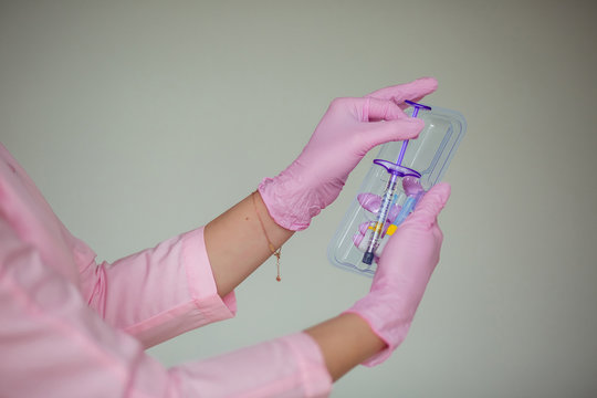 Female Hand In Pink Medical Gloves Holds A Syringe.