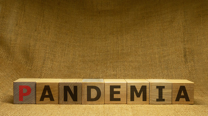 Wooden cubes with red and black word PANDEMIA on sackloth background. Pandemia and Covid-19 concept.