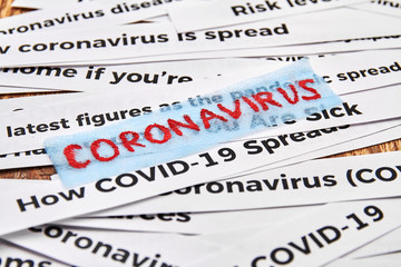 Red Inscription Coronavirus on the background newspaper headline clippings. Concept of COVID-19. Closeup