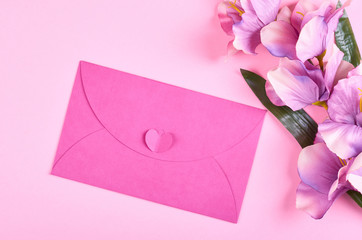Envelope and flowers on pink background composition.
