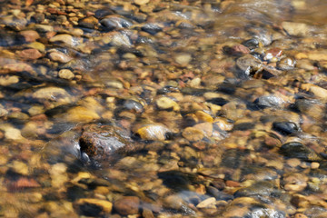 Soft wavy water river with flowing water above the stones