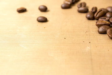Beige background with coffee beans. Roasted Arabica coffee beans scattered on a beige textured background like flax close up with copy space