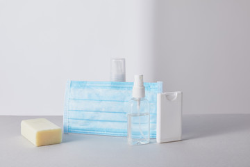 hand sanitizer in bottles, medical mask and antibacterial soap on white background