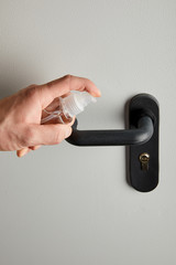cropped view of man disinfecting door handle with antiseptic