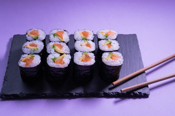 Salmon and avocado maki rolls with chopsticks on a slate plate. Japanese cuisine. 