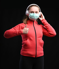 Teen girl in protective sterile medical mask on her face posing over black background