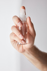 cropped view of man holding hand sanitizer in spray bottle on grey background