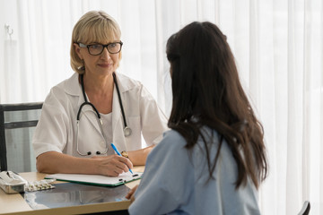 Doctor and Patient are sitting in the clinic and give consult to patient . Doctor is checking the chart and explain the symptoms