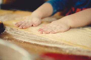 childs hands kneading dough on table