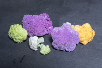 Multi-coloured fresh pieces of cauliflower on dark background