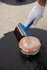 Worker applies bitumen mastic on the foundation