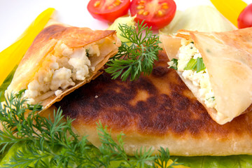 Pita triangles with cottage cheese, herbs, large tomatoes on a white plate