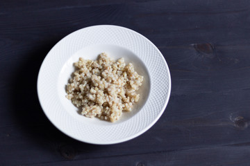 Boiled green buckwheat in white plate  on black background 