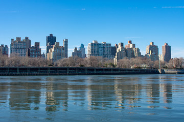 Fototapeta na wymiar Upper East Side New York City Skyline along the East River with a Clear Blue Sky and Reflections