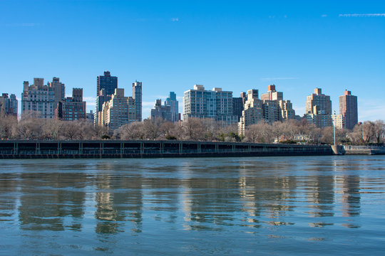 Upper East Side New York City Skyline along the East River with a Clear Blue Sky and Reflections