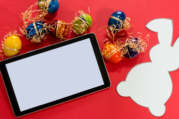 Top view of tablet and easter eggs, paper rabbit.