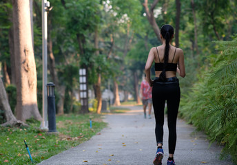 young woman doing exercise in the park and listening music