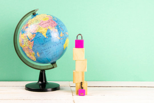 Globe and wooden cubes lined in the shape of a house, along with a pink pad and keys. The concept of renting a home