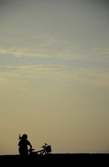 Silueta de mujer con bicicleta al atardecer