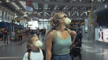Woman and child baby tourist caucasian at airport with wearing protective medical mask. Family in...