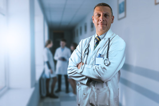 Médico posando de pie con cara de confianza en el pasillo de un hospital