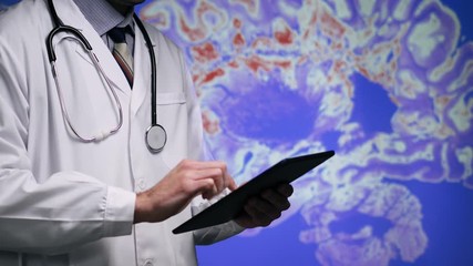 A medical doctor in a white coat and a stethoscope using his tablet computer to look at a contrast MRI image scan of a brain and adding notes. Public Domain background element from U.S. Centers for Di - Powered by Adobe