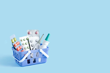 purchase, delivery of medicines to your home. home first aid kit for colds, illnesses, viruses, epidemics. online purchase of medicines. drugs in basket on blue background, copy space