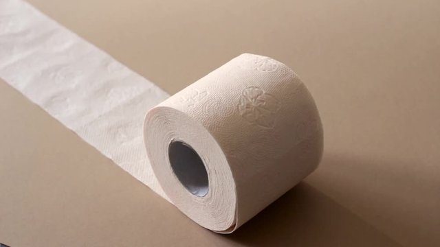 rolls of peach beige toilet paper rolling on beige background