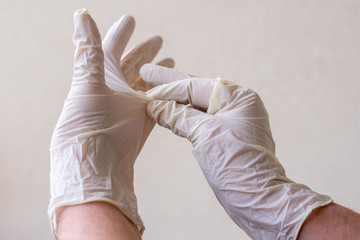 Women's hands with latex gloves, removing gloves safely and effectively to avoid contagion.