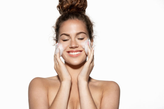 Smiling woman  washing face, applying soap makeup and dirty removal facial cosmetics product