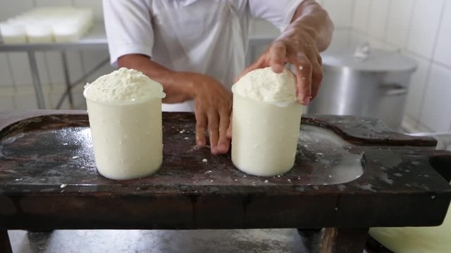 Close up of man's hand squeezing rennet milk in the form of plastic to make the famous artisan cured cheese from Minas Gerais on a white cotton cloth. Concept of gourmet, food, cook, healthy, organic 